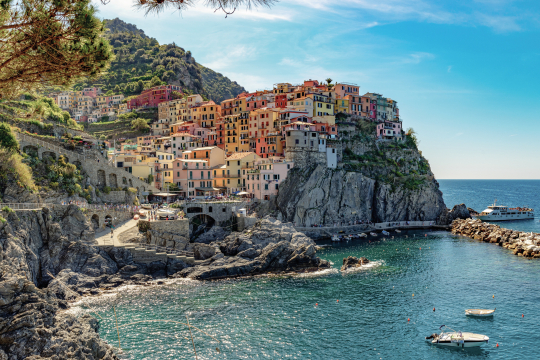 Blick auf ein kleines Dorf auf einem Felsen gelegen mit bunten kleinen Häusern, rechts das Meer